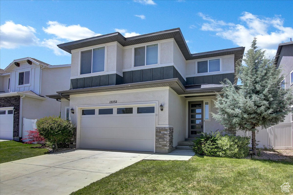 View of front of property featuring stone siding, a garage, stucco siding, and driveway