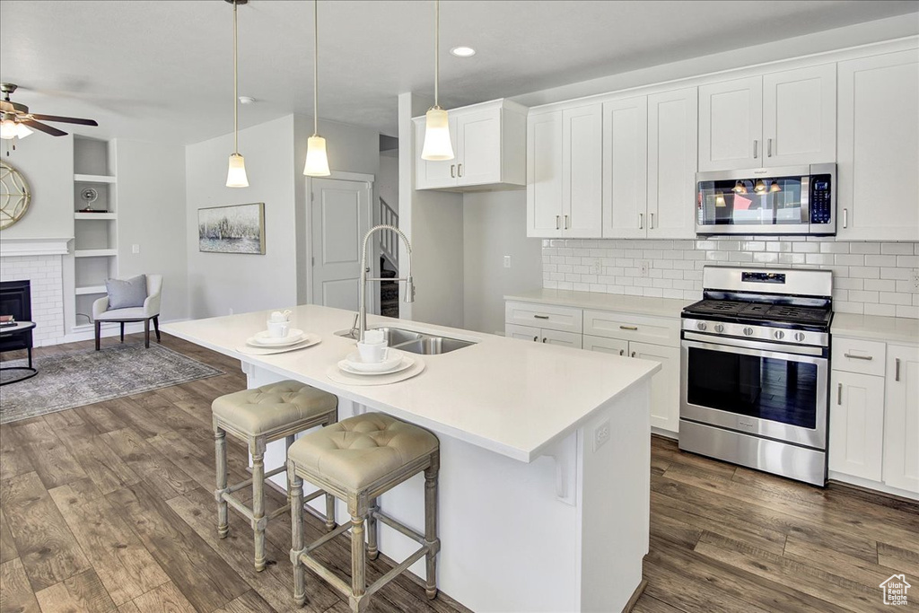 Kitchen featuring appliances with stainless steel finishes, dark wood-style floors, ceiling fan, open floor plan, and white cabinets