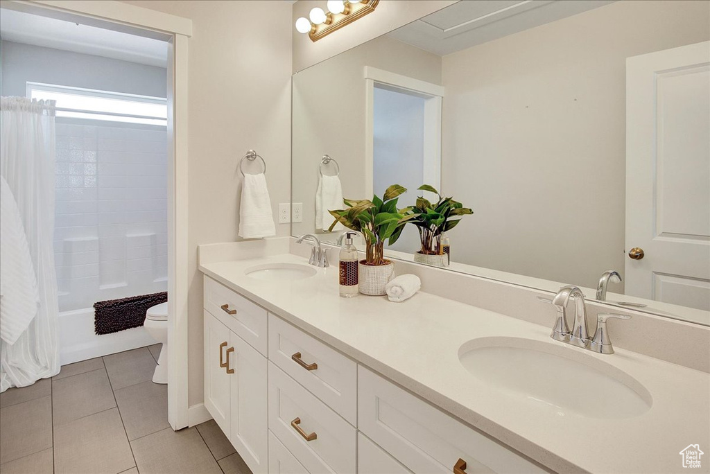 Bathroom with double vanity, tile patterned floors, and shower / tub combo