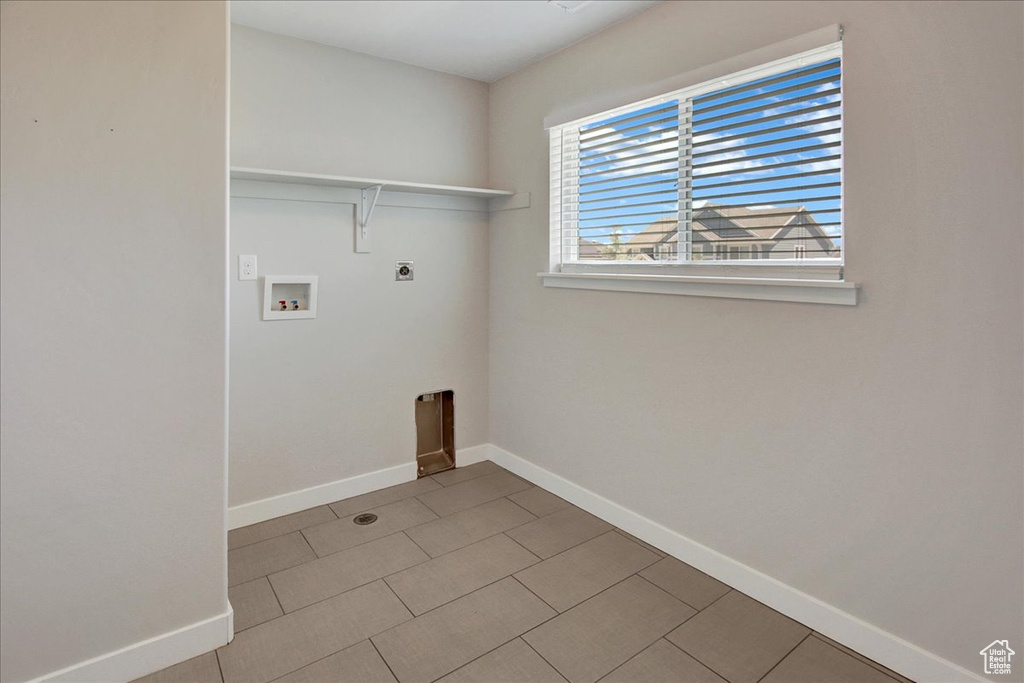 Laundry area with hookup for an electric dryer, hookup for a washing machine, and tile patterned flooring