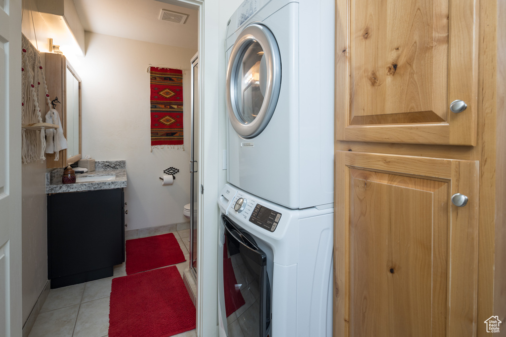 Laundry area featuring stacked washing machine and dryer and light tile patterned floors