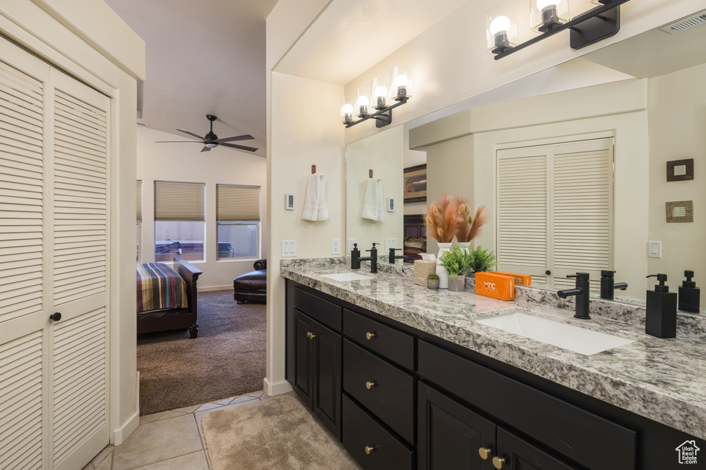 Ensuite bathroom featuring a closet, double vanity, a ceiling fan, and tile patterned floors