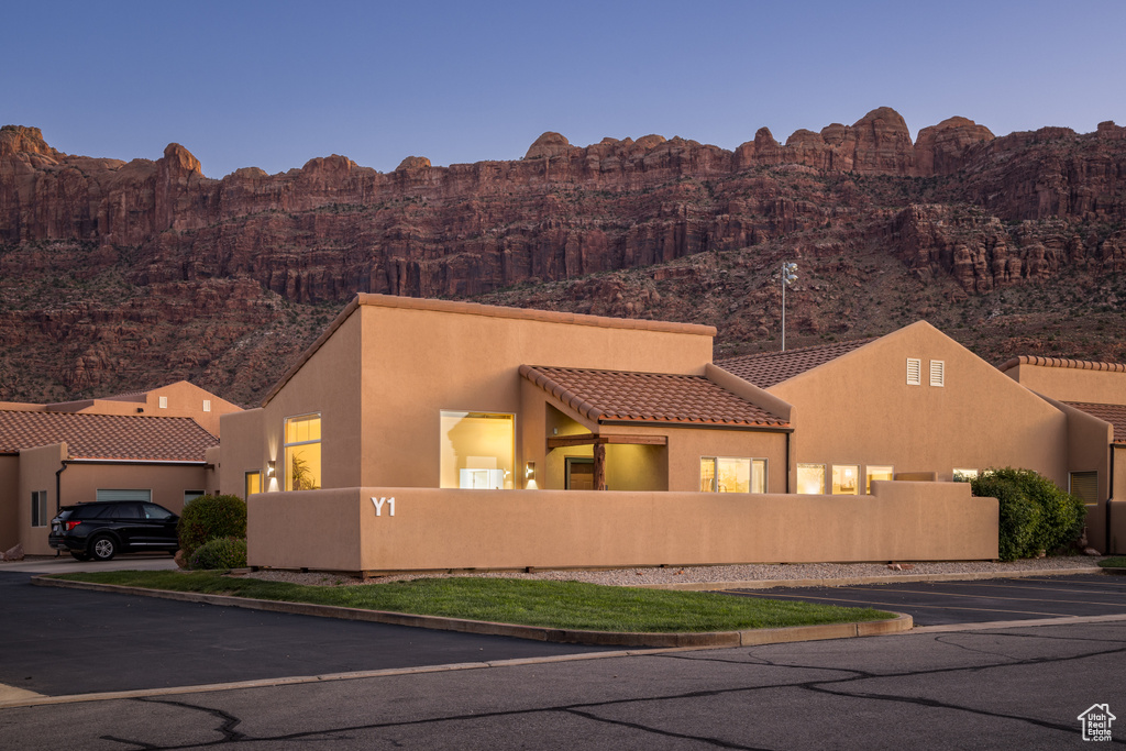 Pueblo-style home with stucco siding, a mountain view, and a tiled roof