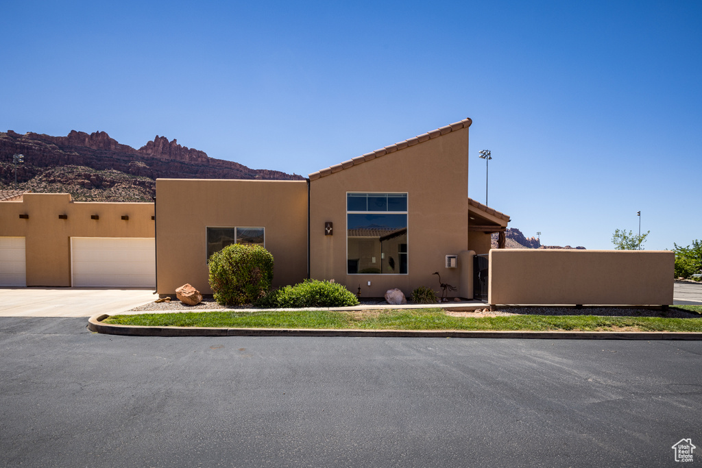 Pueblo revival-style home featuring a garage, concrete driveway, stucco siding, and a mountain view