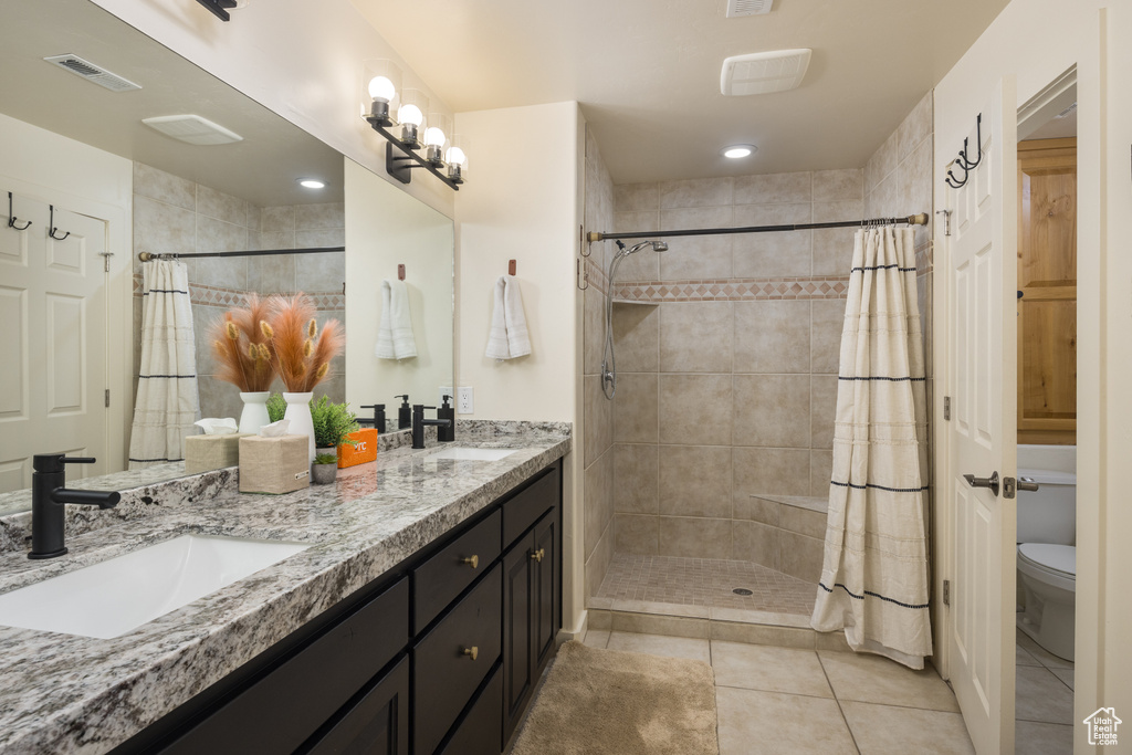 Bathroom with a tile shower, double vanity, and tile patterned floors