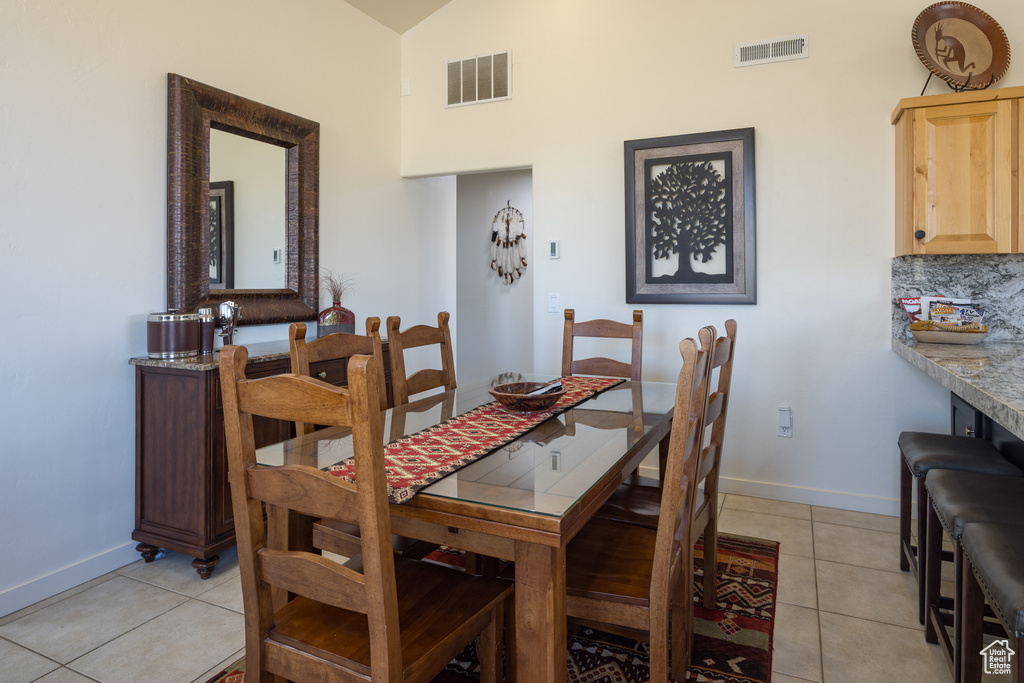 Dining area with light tile patterned floors and high vaulted ceiling