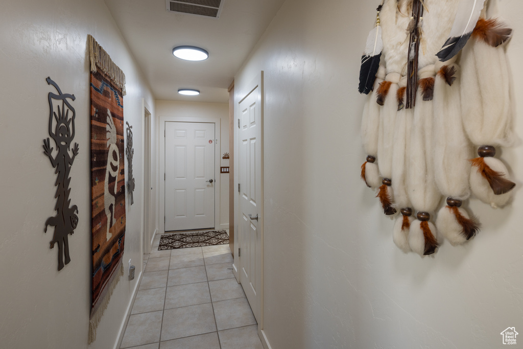 Hallway with light tile patterned flooring and baseboards