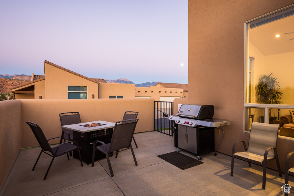 Patio terrace at dusk featuring area for grilling, a mountain view, a fire pit, and a patio