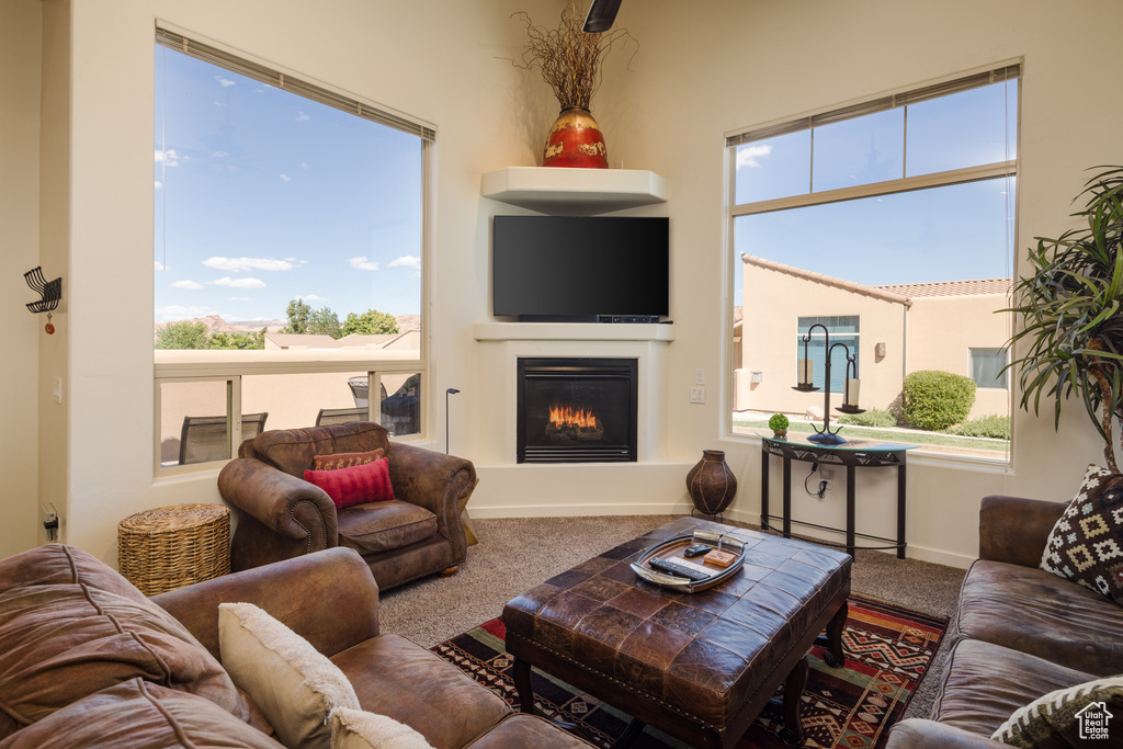 Living area with carpet flooring, a glass covered fireplace, and plenty of natural light