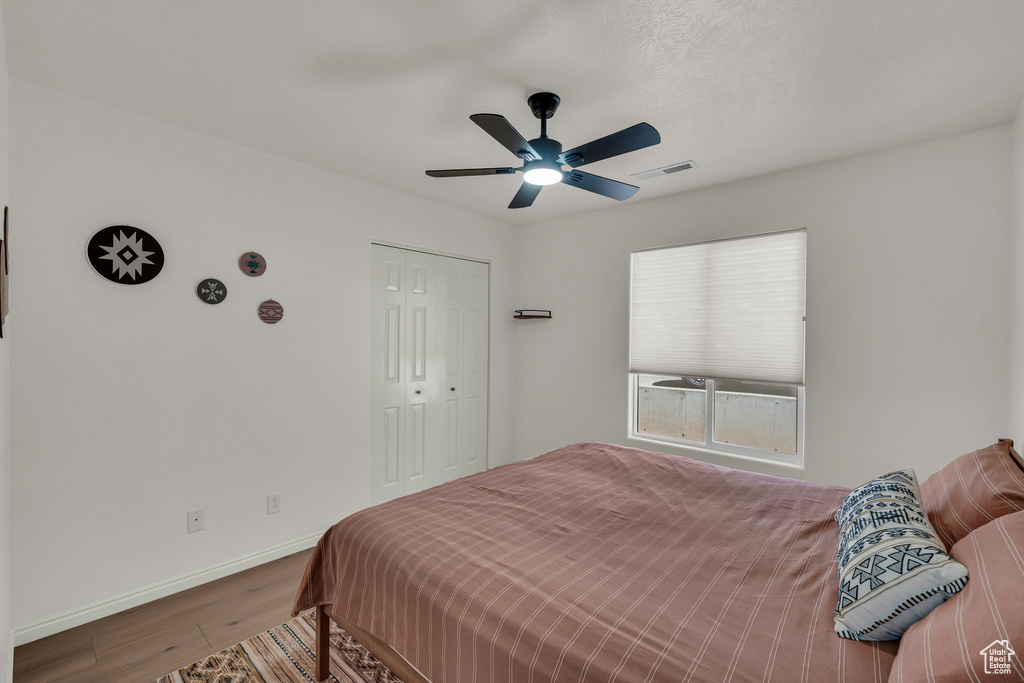 Bedroom with wood finished floors, a closet, and a ceiling fan