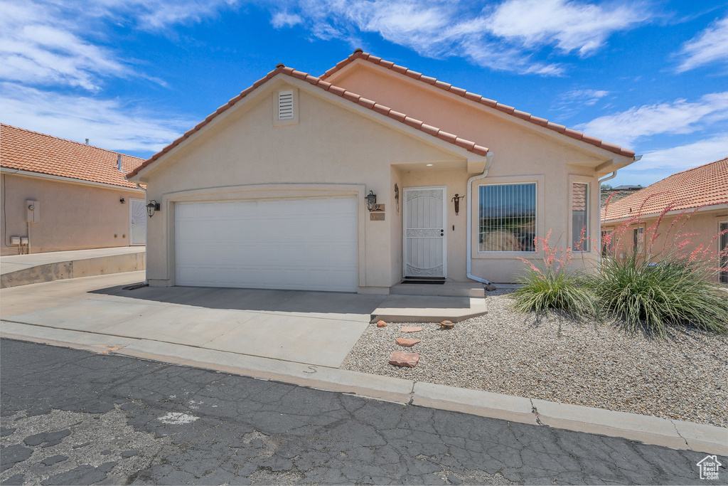 Mediterranean / spanish-style home with an attached garage, driveway, stucco siding, and a tiled roof