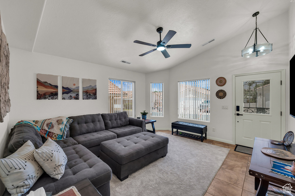 Living room with lofted ceiling, a ceiling fan, and light tile patterned floors