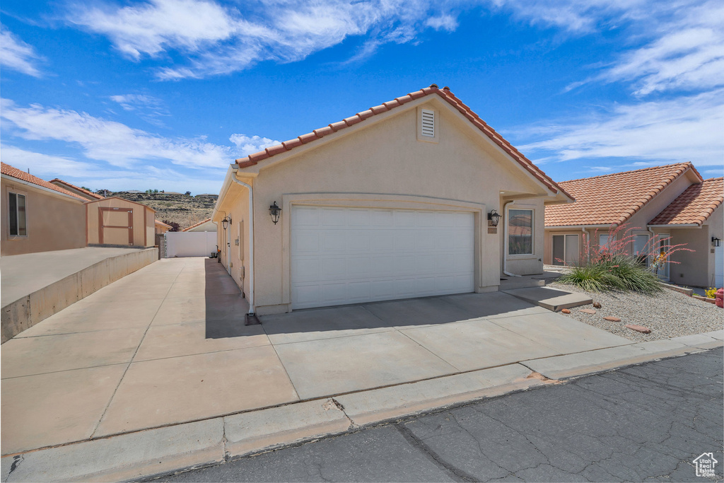 View of front of property with driveway, a garage, stucco siding, and a tile roof