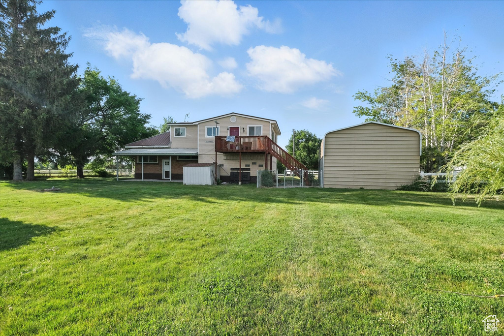 Back of property featuring a shed, stairway, a lawn, and a wooden deck