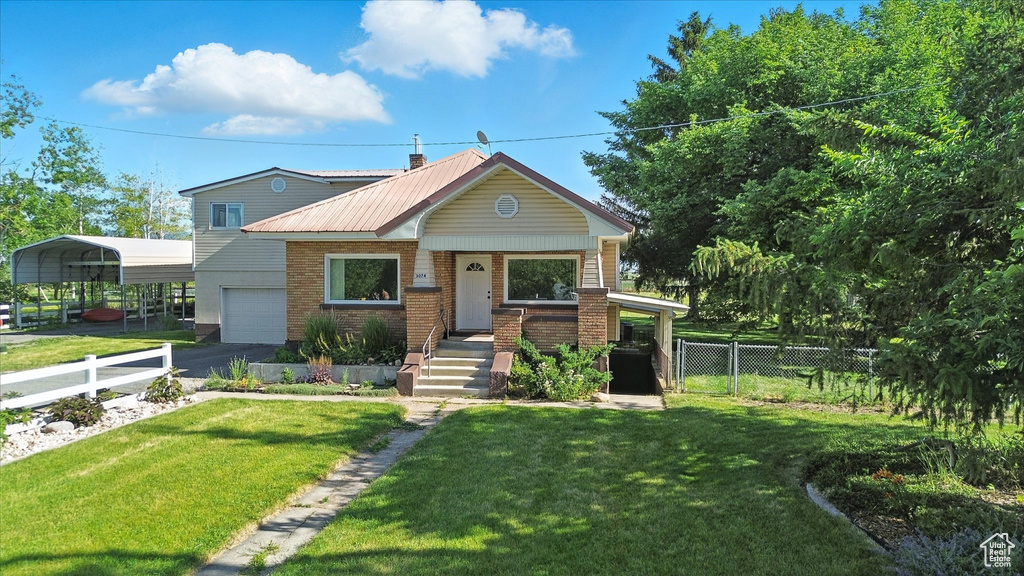 View of front of house featuring an attached garage, asphalt driveway, a metal roof, brick siding, and a porch