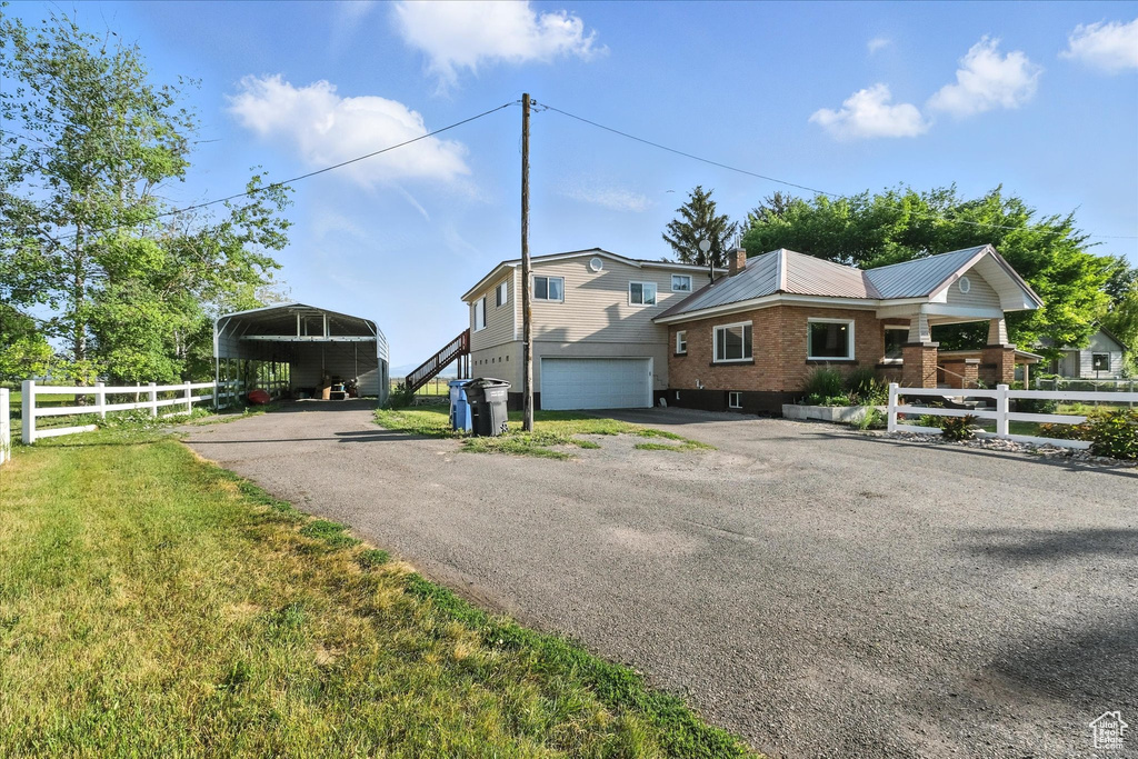 View of front of property featuring asphalt driveway, a detached carport, an attached garage, and brick siding