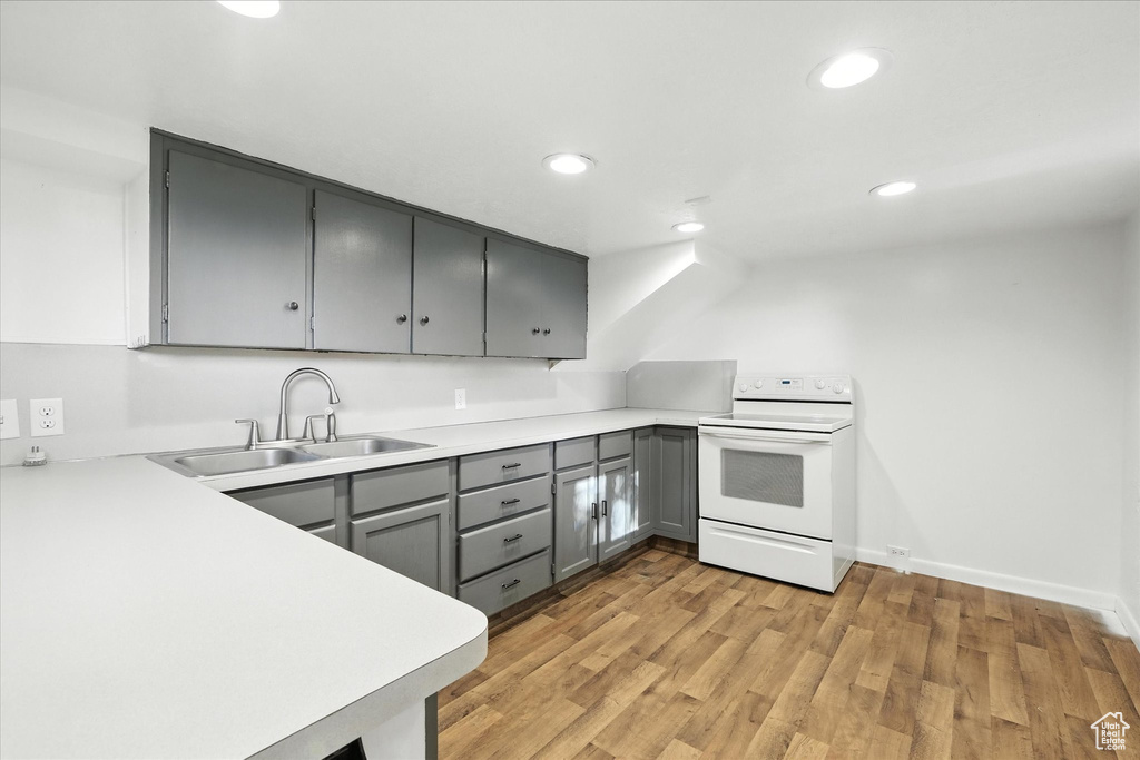 Kitchen with white range with electric stovetop, gray cabinets, light wood-style flooring, light countertops, and recessed lighting