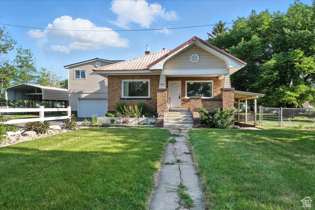 View of front of home featuring brick siding, a garage, a detached carport, a gate, and a metal roof