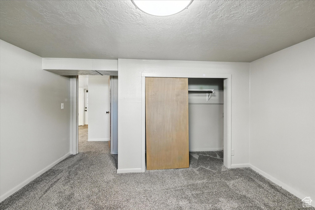 Unfurnished bedroom featuring carpet floors, a closet, and a textured ceiling