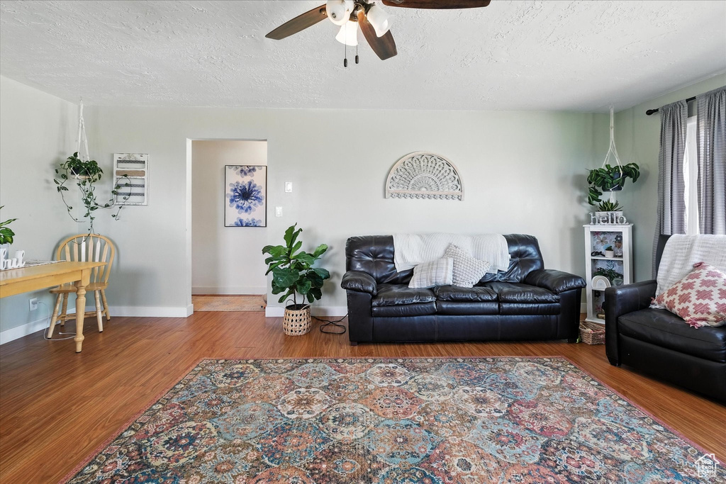 Living area with a ceiling fan, wood finished floors, and a textured ceiling