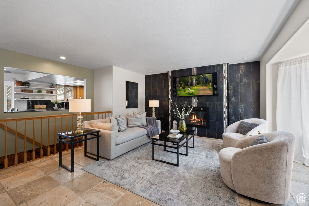 Living room featuring a tiled fireplace, stone tile floors, recessed lighting, and stairway