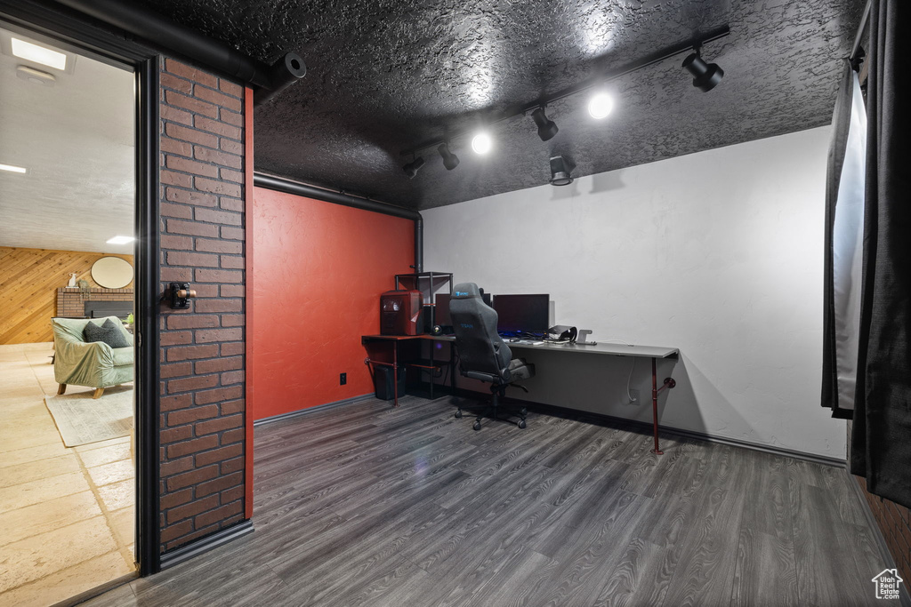 Office with wood finished floors, wooden walls, and track lighting