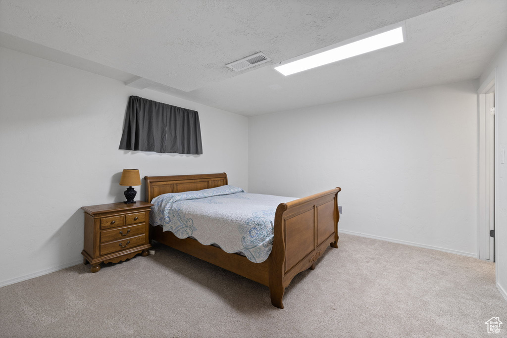 Bedroom with light colored carpet and a textured ceiling
