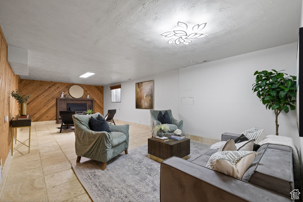 Living room with wooden walls, a fireplace, and a textured ceiling