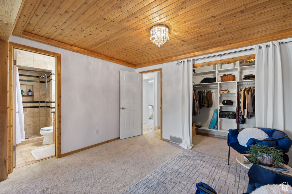 Carpeted bedroom featuring a closet, wood ceiling, ensuite bathroom, and a chandelier
