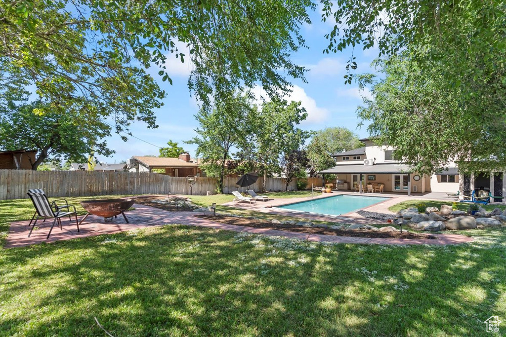 View of swimming pool with an outdoor fire pit, a patio area, and a fenced backyard
