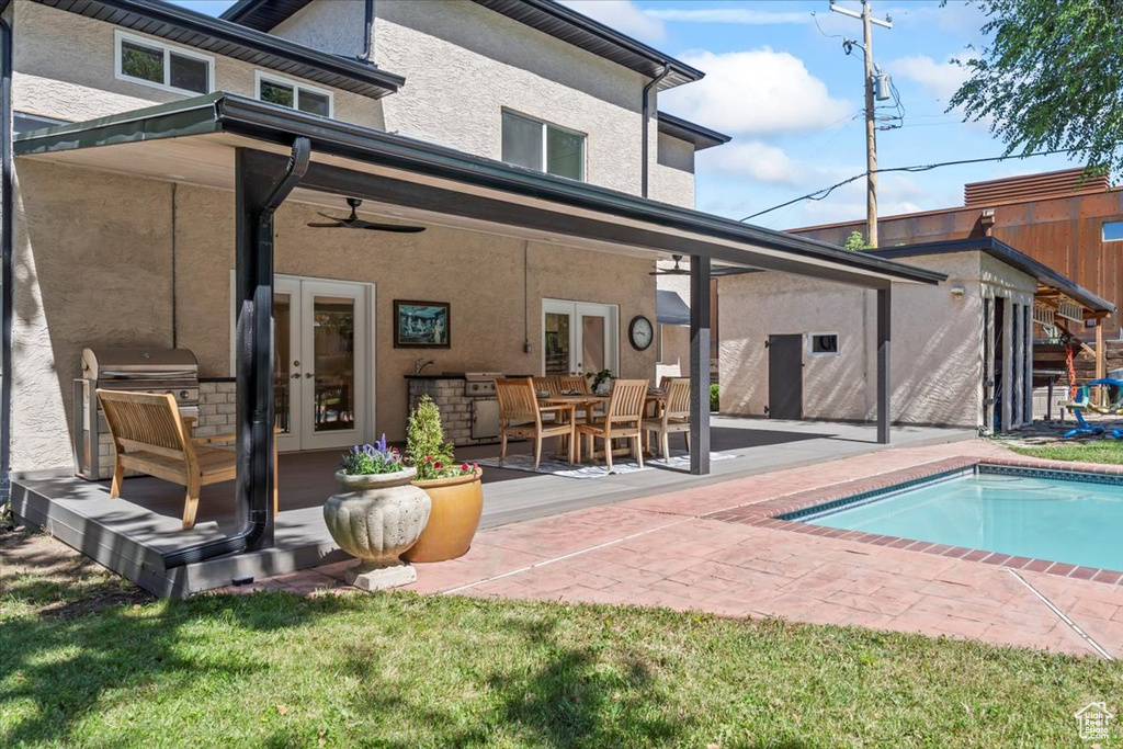 Rear view of property featuring french doors, a patio, an outdoor pool, and stucco siding