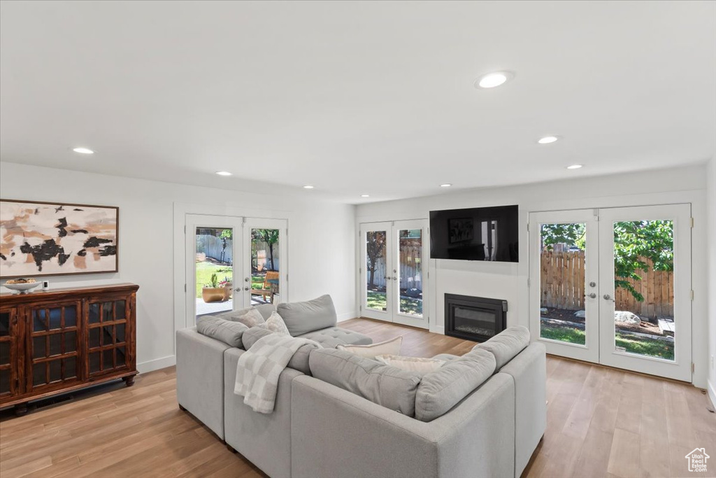 Living area featuring french doors, light wood-style flooring, recessed lighting, and a glass covered fireplace