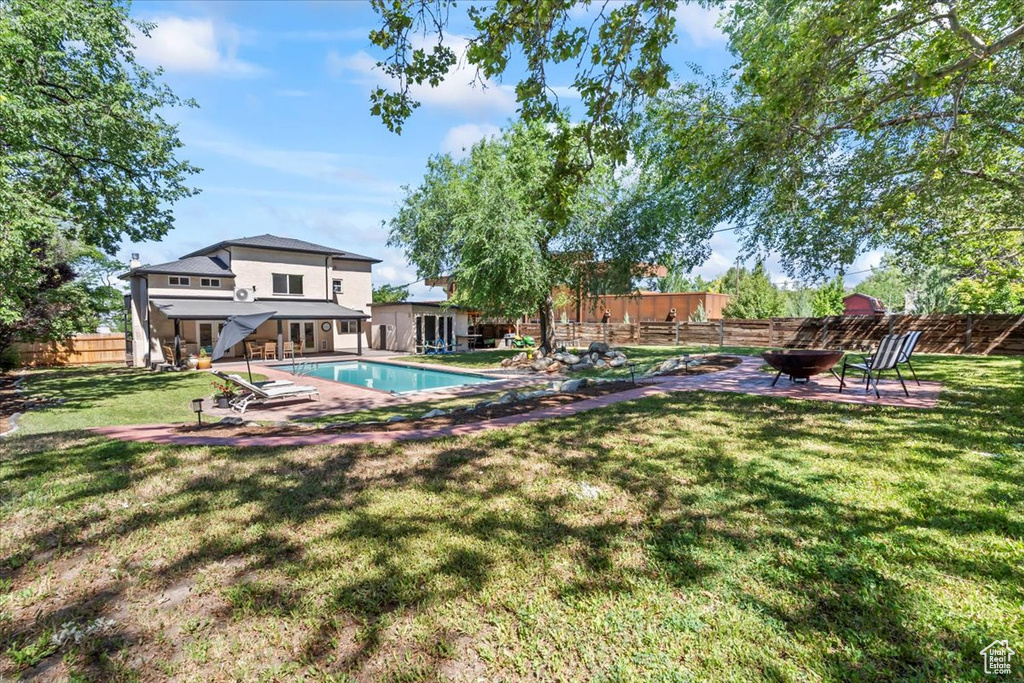 View of swimming pool featuring an outdoor fire pit, a fenced backyard, and a patio area
