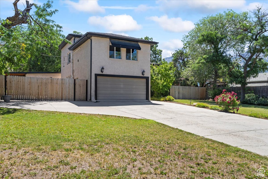 View of front facade featuring an attached garage, stucco siding, and concrete driveway