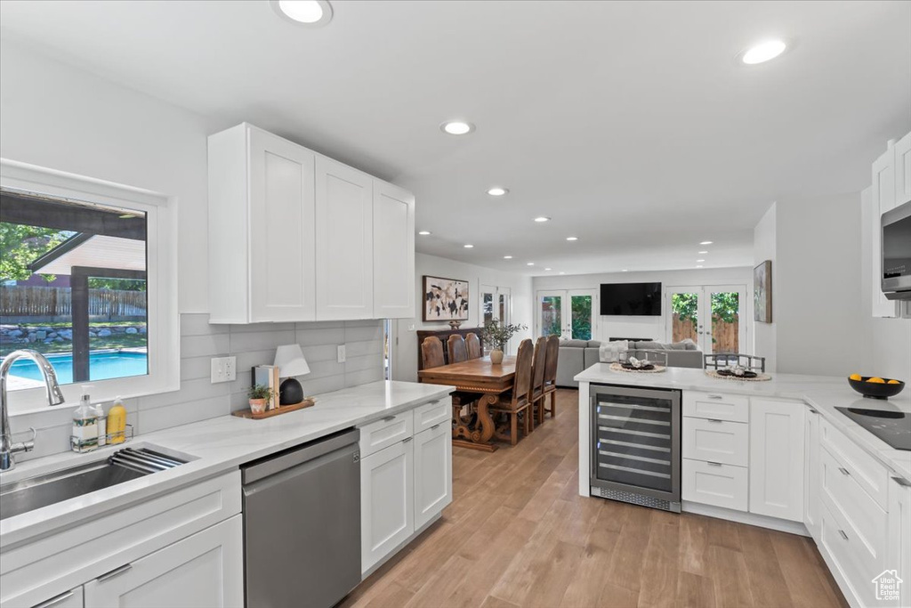 Kitchen with wine cooler, stainless steel appliances, recessed lighting, white cabinetry, and decorative backsplash