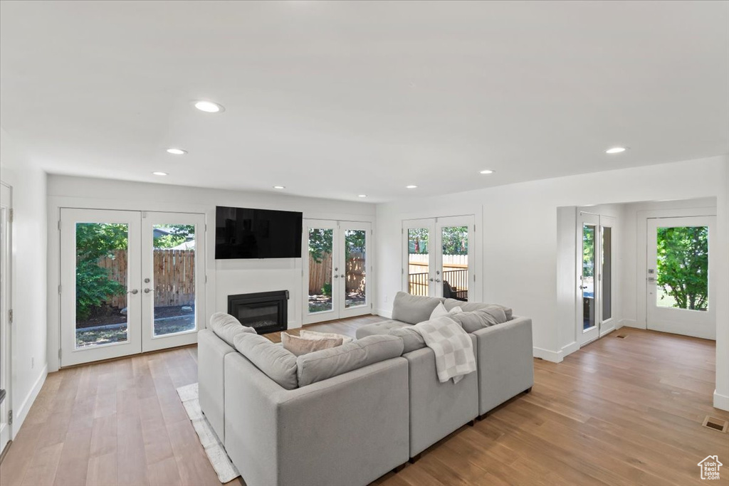 Living area with french doors, light wood-type flooring, recessed lighting, and a glass covered fireplace