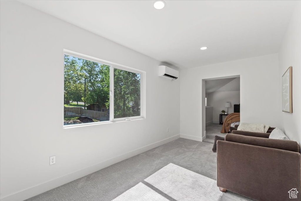 Living area featuring a wall mounted AC, carpet flooring, and recessed lighting