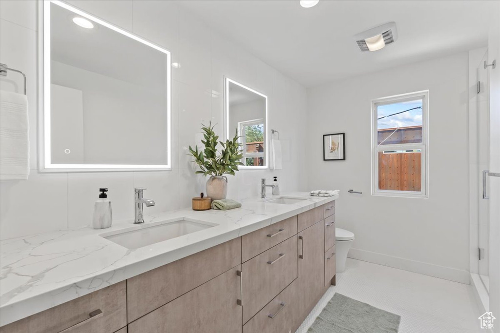 Full bathroom with double vanity, plenty of natural light, and tile patterned floors
