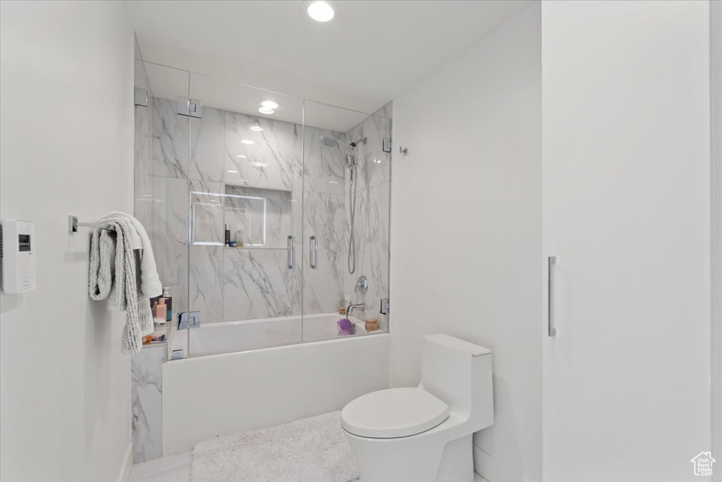 Bathroom with combined bath / shower with glass door and recessed lighting