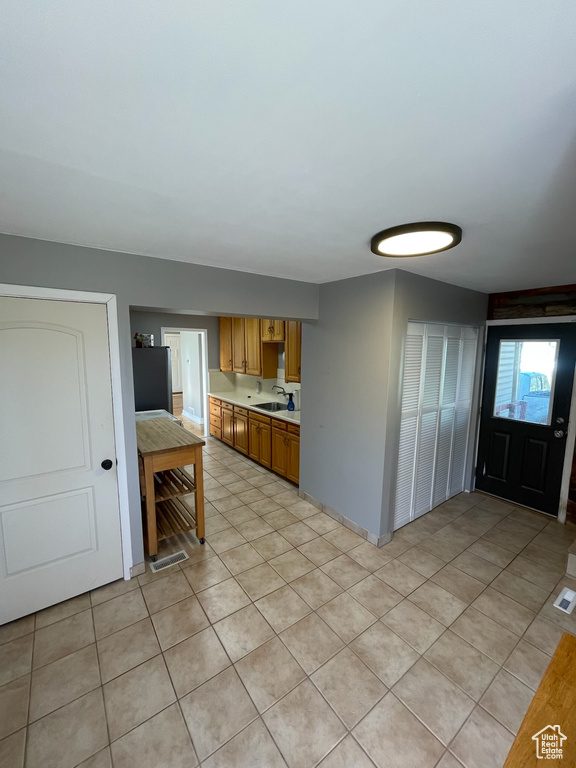 Kitchen with light countertops, light tile patterned flooring, and brown cabinetry