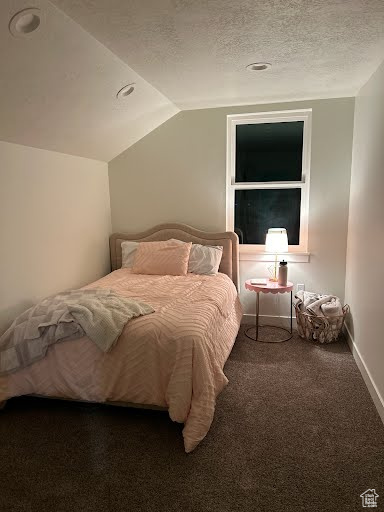 Bedroom with lofted ceiling, carpet, and a textured ceiling