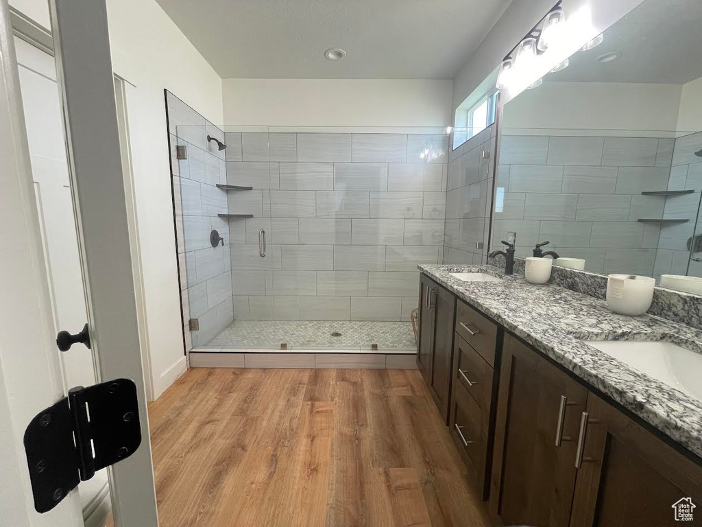 Full bathroom with a stall shower, double vanity, and wood finished floors