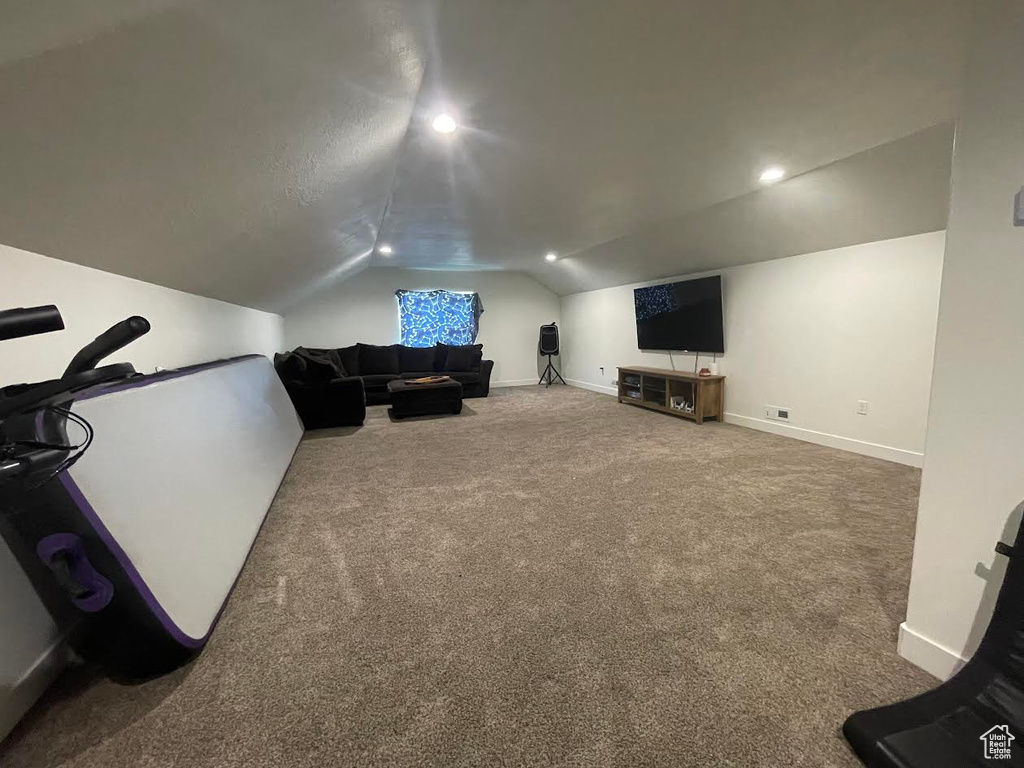 Carpeted living area featuring vaulted ceiling and baseboards