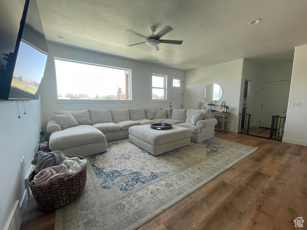 Living area with ceiling fan, wood finished floors, and a textured ceiling