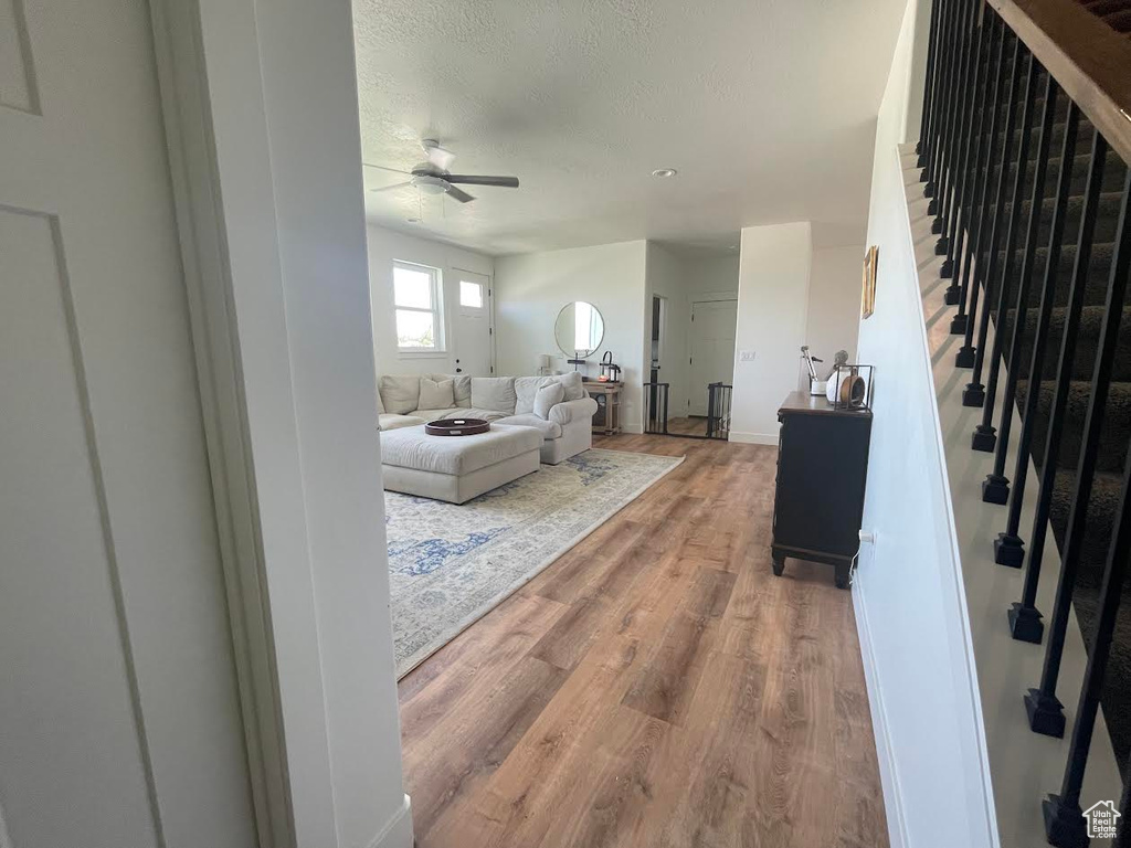 Living area featuring a ceiling fan, wood finished floors, stairs, and a textured ceiling