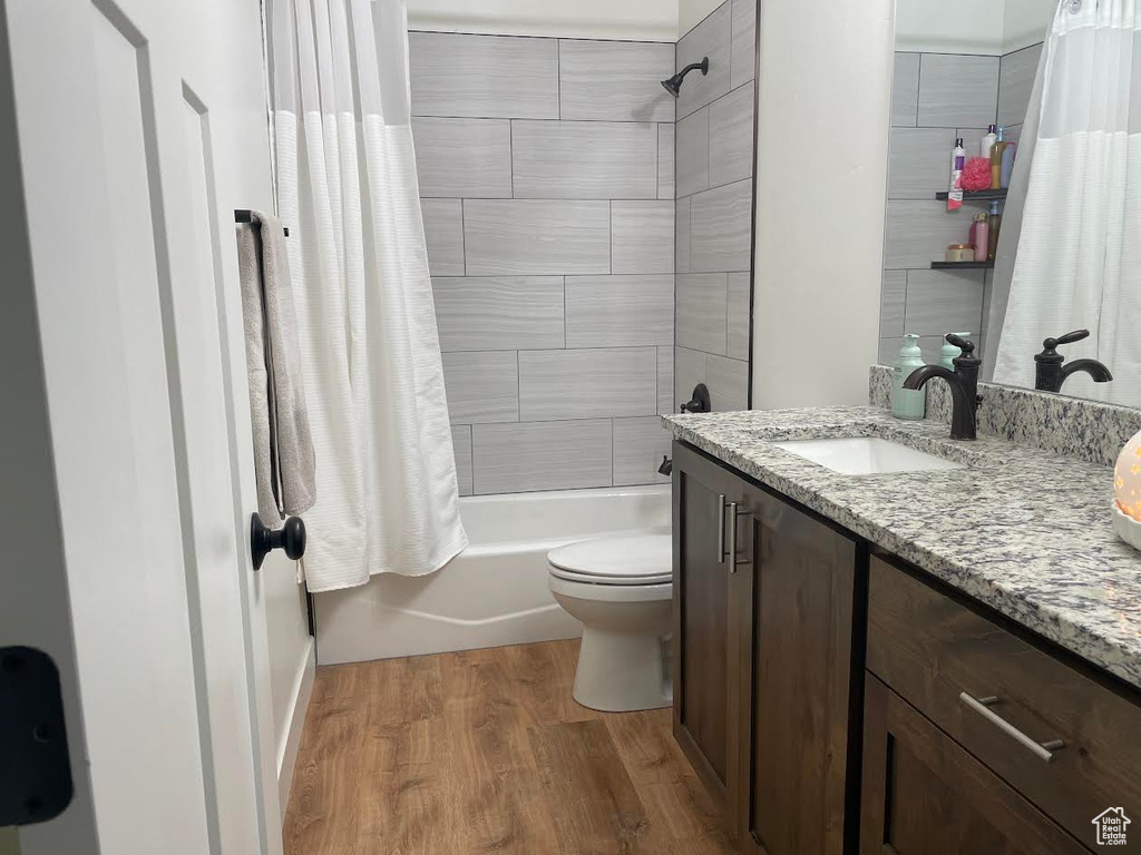 Full bathroom featuring vanity, shower / bath combo with shower curtain, and wood finished floors