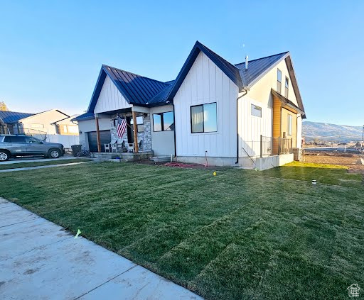 View of front facade featuring board and batten siding, a front yard, a metal roof, and a standing seam roof