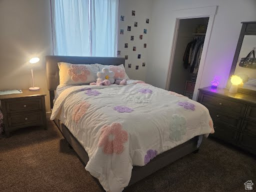 Bedroom with dark colored carpet and a closet