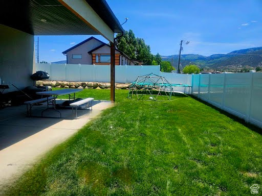 Fenced backyard with a mountain view and a patio area