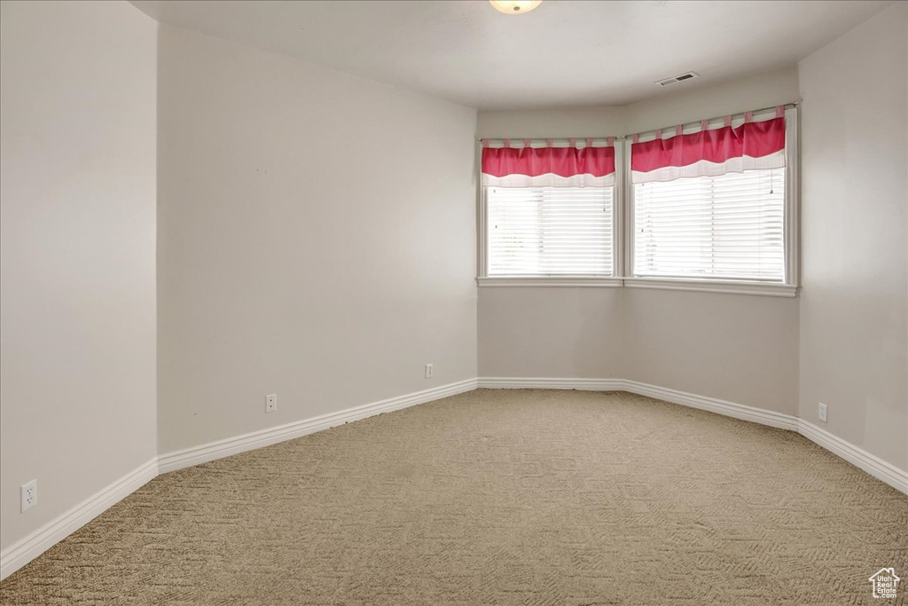 Carpeted empty room featuring baseboards
